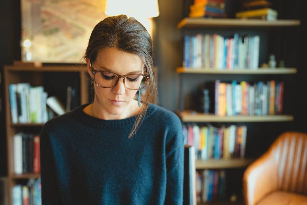 Portrait of a woman editor in her forties with glasses in a home library